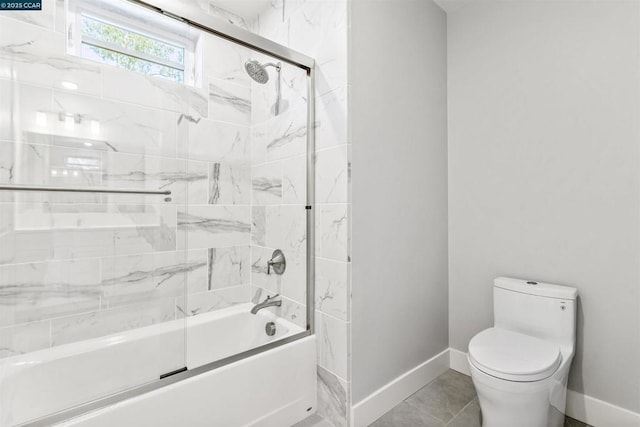 bathroom featuring toilet, bath / shower combo with glass door, and tile patterned flooring