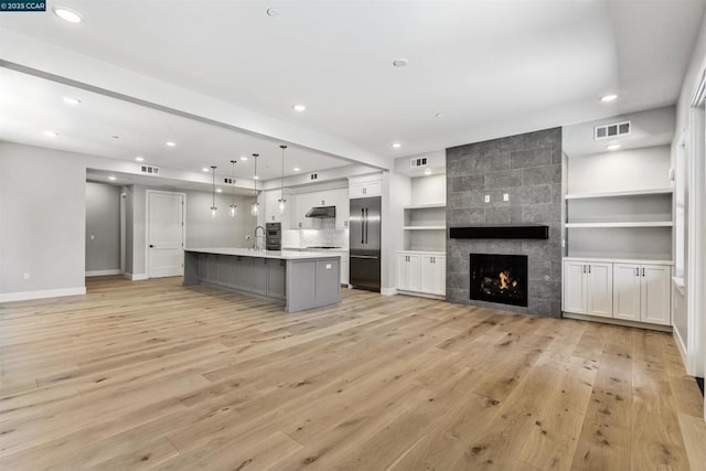 unfurnished living room featuring sink, light hardwood / wood-style flooring, and a fireplace