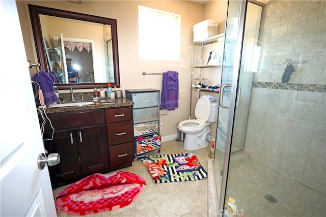 bathroom featuring a shower with shower door, vanity, toilet, and tile patterned floors