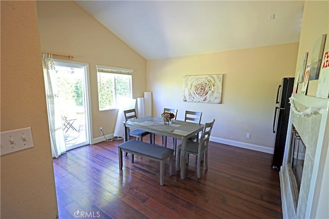 dining area featuring a premium fireplace, dark hardwood / wood-style flooring, and high vaulted ceiling