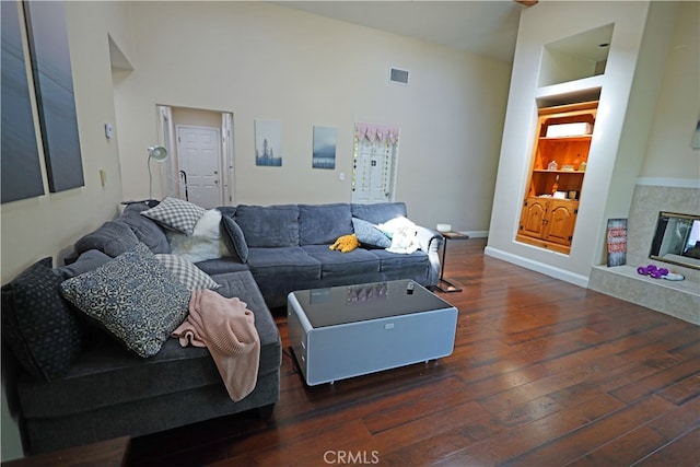 living room featuring built in features, dark hardwood / wood-style floors, and a towering ceiling