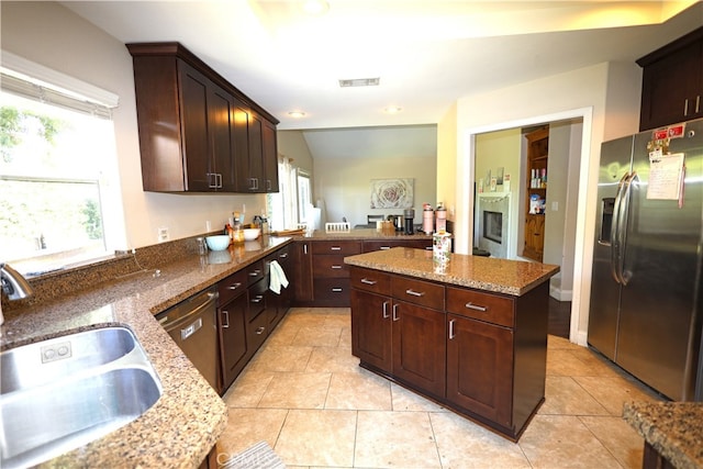 kitchen with sink, appliances with stainless steel finishes, light stone counters, and a wealth of natural light