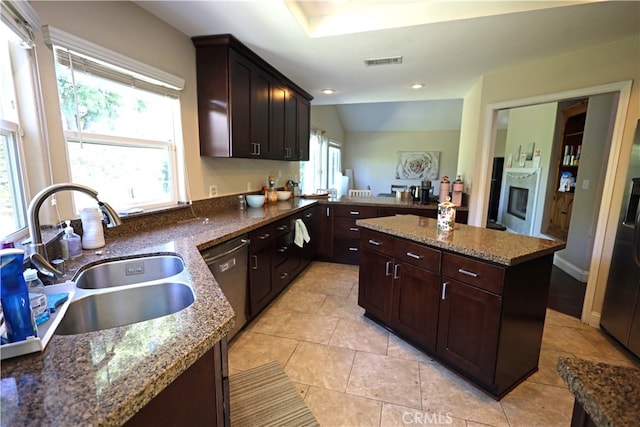 kitchen with dishwasher, stone counters, sink, and light tile patterned floors