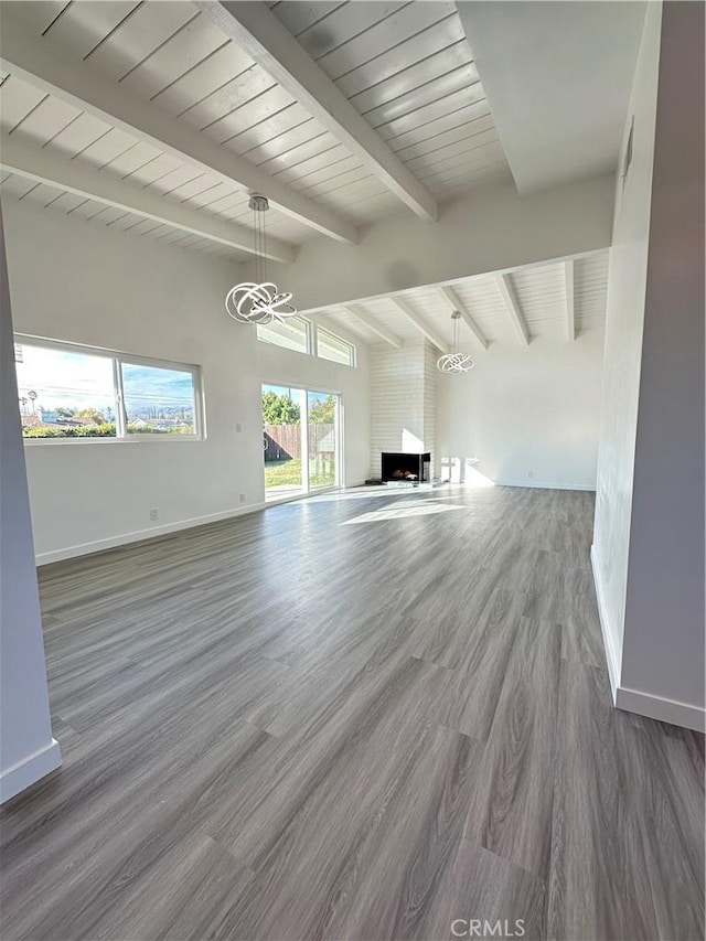 unfurnished living room with a fireplace, vaulted ceiling with beams, a chandelier, and dark wood-type flooring