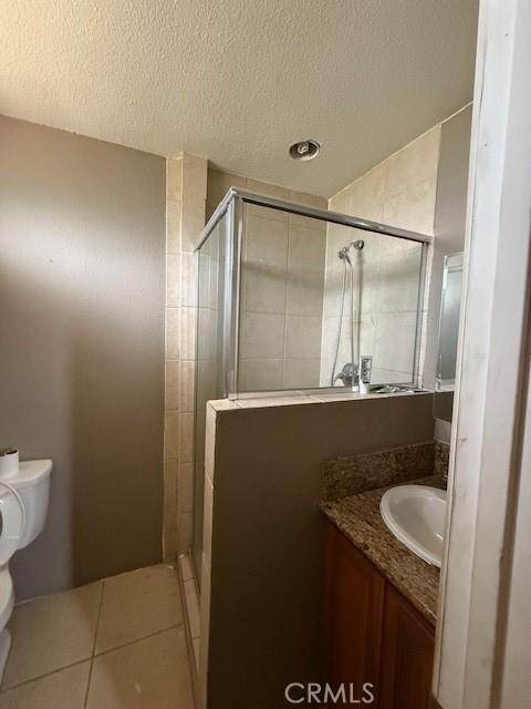 24062 Eucalyptus Ave, Moreno Valley, CA 92553 - bathroom with a textured ceiling, a stall shower, vanity, tile patterned floors, and toilet