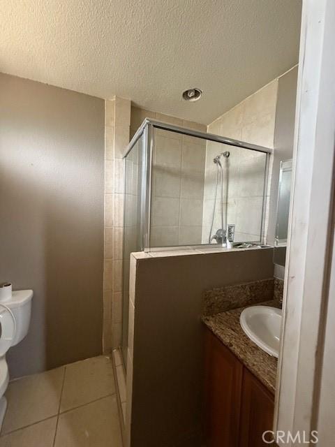 24062 Eucalyptus Ave, Moreno Valley, CA 92553 - full bathroom with a textured ceiling, tile patterned flooring, a shower stall, vanity, and toilet