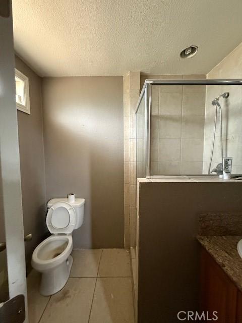 24062 Eucalyptus Ave, Moreno Valley, CA 92553 - bathroom featuring tile patterned flooring, vanity, toilet, a textured ceiling, and a stall shower