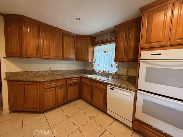 24062 Eucalyptus Ave, Moreno Valley, CA 92553 - kitchen featuring a sink, brown cabinetry, white appliances, and light tile patterned flooring