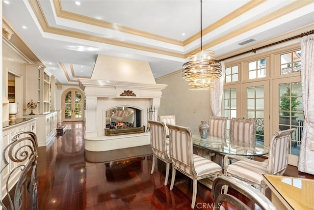 dining area featuring a raised ceiling, dark hardwood / wood-style flooring, crown molding, and french doors