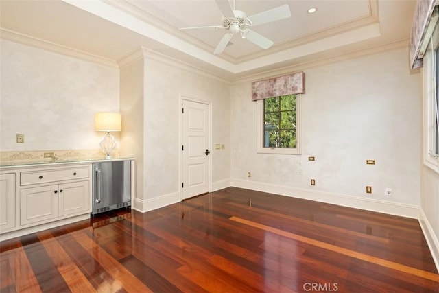 spare room with dark hardwood / wood-style flooring, a tray ceiling, ceiling fan, and crown molding