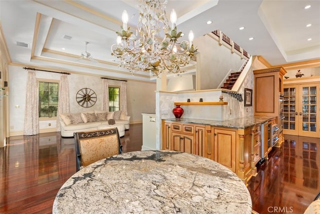 dining room with french doors, ceiling fan with notable chandelier, a raised ceiling, and dark wood-type flooring