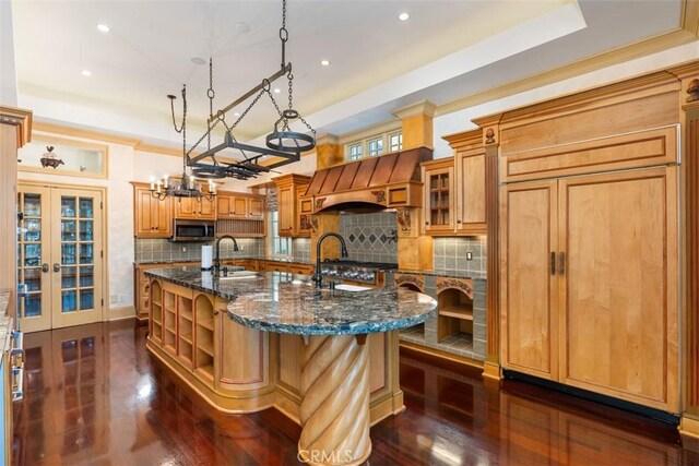 kitchen with tasteful backsplash, stainless steel appliances, dark wood-type flooring, pendant lighting, and a center island with sink