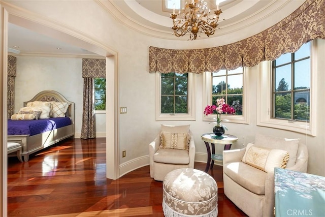 living area with a chandelier, ornamental molding, a tray ceiling, and dark wood-type flooring