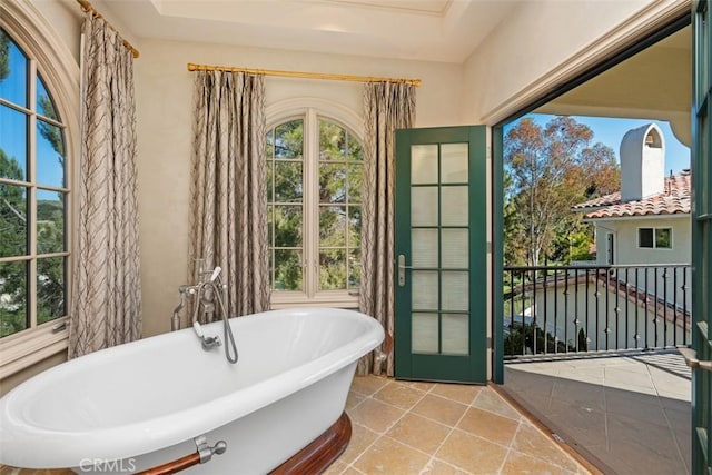 bathroom featuring tile patterned floors, a washtub, and a tray ceiling