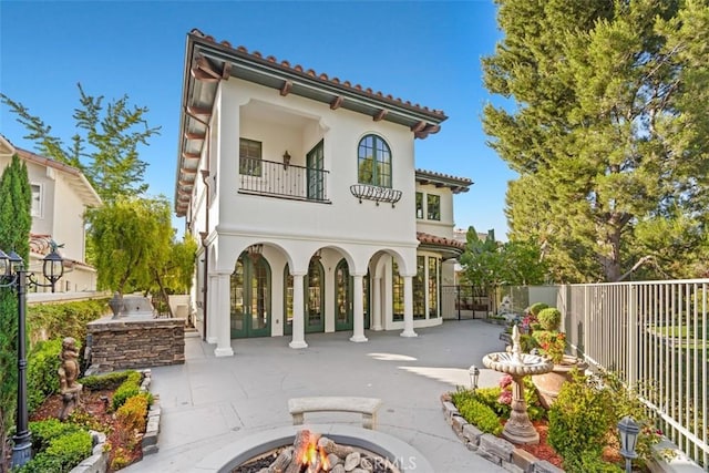 rear view of property featuring a patio, area for grilling, and a fire pit