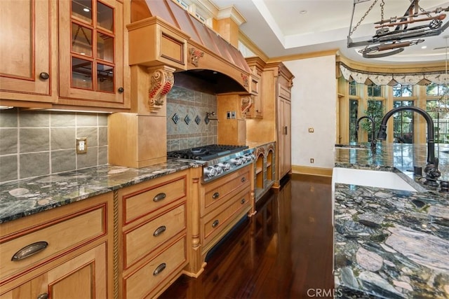 kitchen featuring sink, dark stone counters, stainless steel gas stovetop, decorative backsplash, and custom exhaust hood