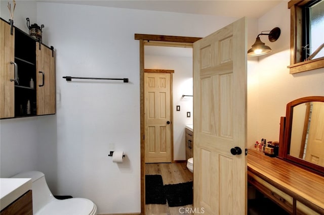 bathroom with wood-type flooring, vanity, and toilet