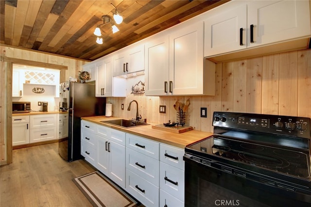 kitchen featuring appliances with stainless steel finishes, white cabinetry, light hardwood / wood-style flooring, wood counters, and sink