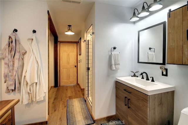 bathroom featuring wood-type flooring, vanity, and walk in shower