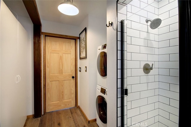 bathroom featuring a tile shower, stacked washer / drying machine, and hardwood / wood-style flooring