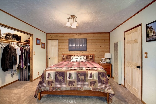 carpeted bedroom featuring a textured ceiling, crown molding, wood walls, and a closet