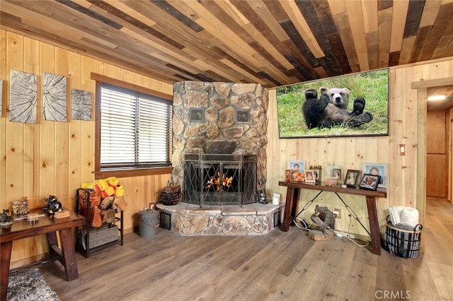 living room featuring wooden walls, hardwood / wood-style floors, wooden ceiling, and a fireplace