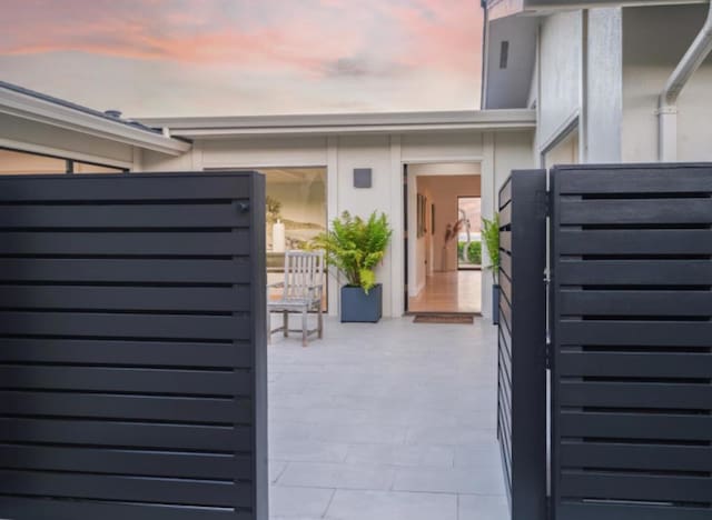 gate at dusk featuring a patio