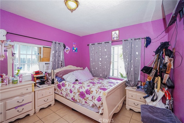 bedroom with cooling unit, multiple windows, light tile patterned floors, and a textured ceiling