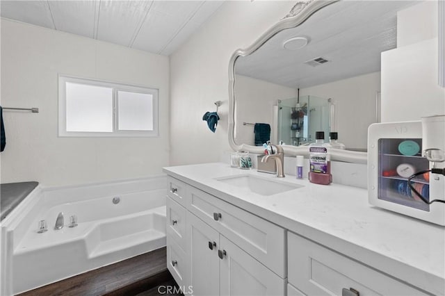 bathroom featuring wood-type flooring, vanity, and a bath