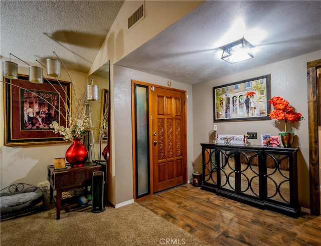 entryway featuring hardwood / wood-style flooring, lofted ceiling, and a textured ceiling