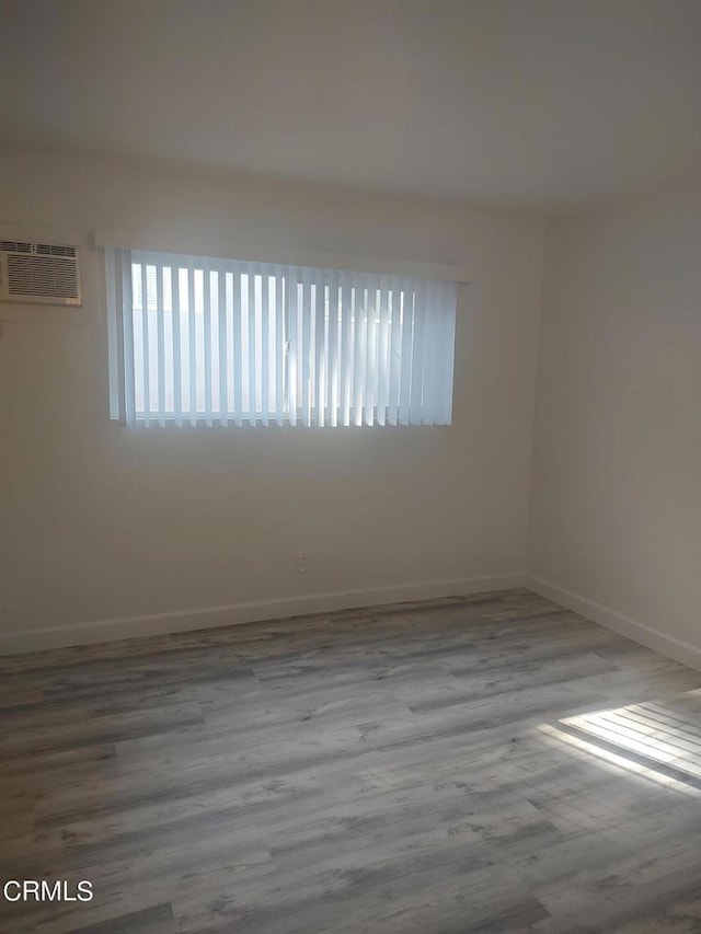 spare room with light wood-type flooring and a wall unit AC