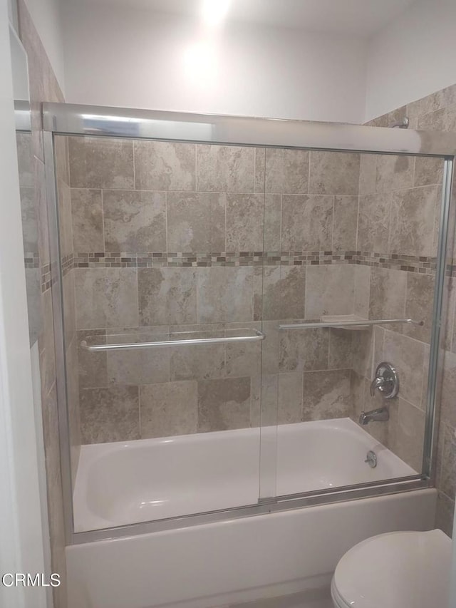 bathroom with bath / shower combo with glass door and toilet