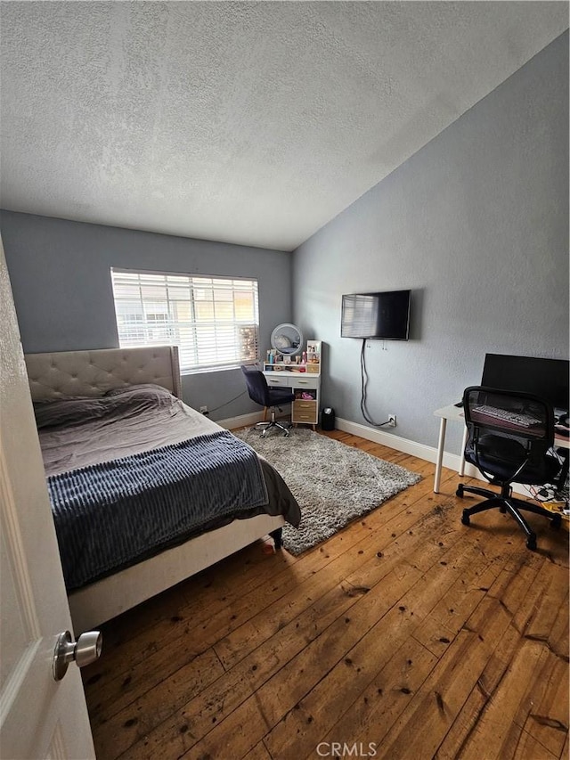 bedroom with a textured ceiling, hardwood / wood-style flooring, and lofted ceiling