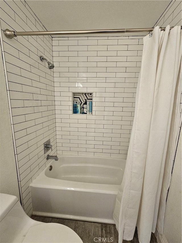 bathroom featuring wood-type flooring, shower / tub combo, and toilet