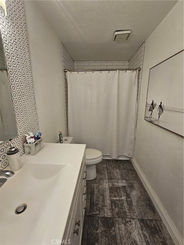 bathroom with vanity, curtained shower, toilet, and a textured ceiling