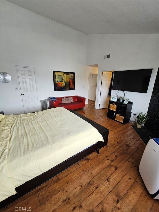 bedroom with radiator, dark hardwood / wood-style flooring, and high vaulted ceiling