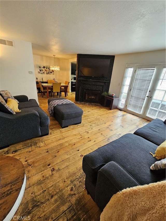 living room with wood-type flooring, a textured ceiling, and a brick fireplace