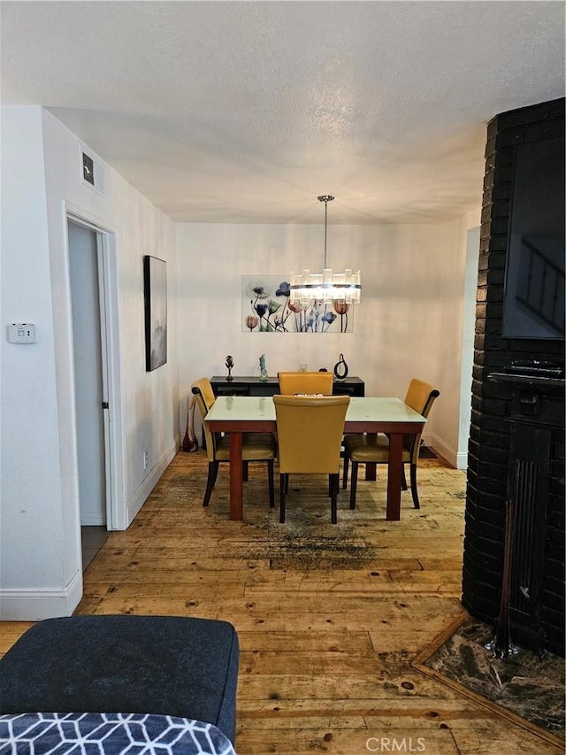 dining area featuring a fireplace, wood-type flooring, and an inviting chandelier