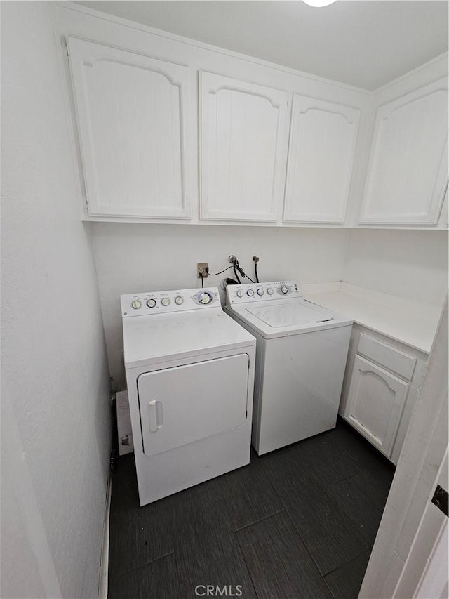 laundry room with dark wood-type flooring, cabinet space, and washer and clothes dryer