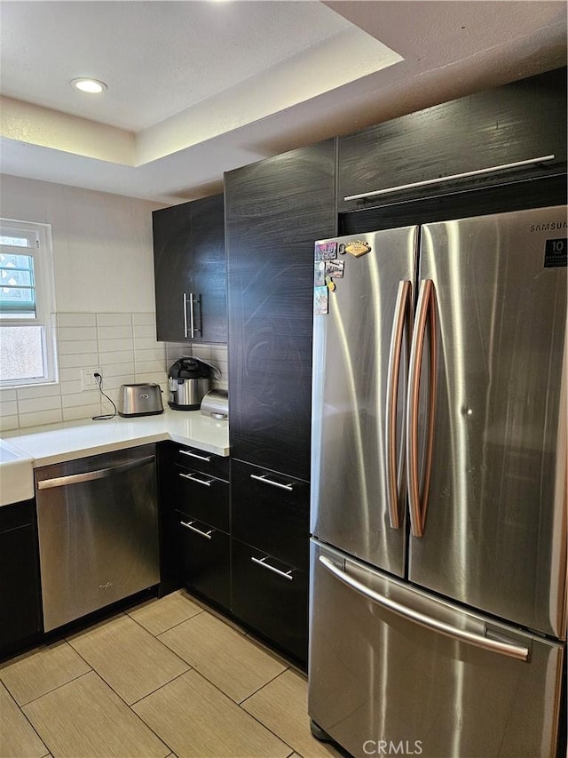 kitchen featuring stainless steel appliances, a raised ceiling, and tasteful backsplash