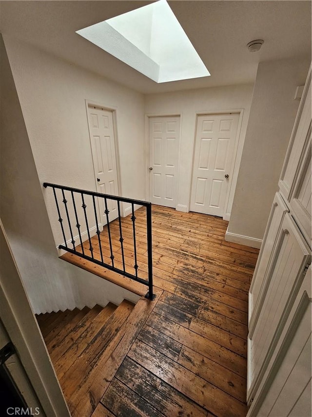 stairway with a skylight and wood-type flooring