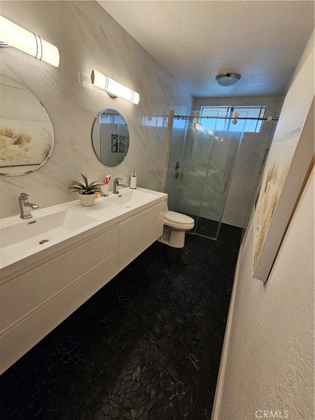 full bath featuring double vanity, a stall shower, a sink, tile walls, and toilet