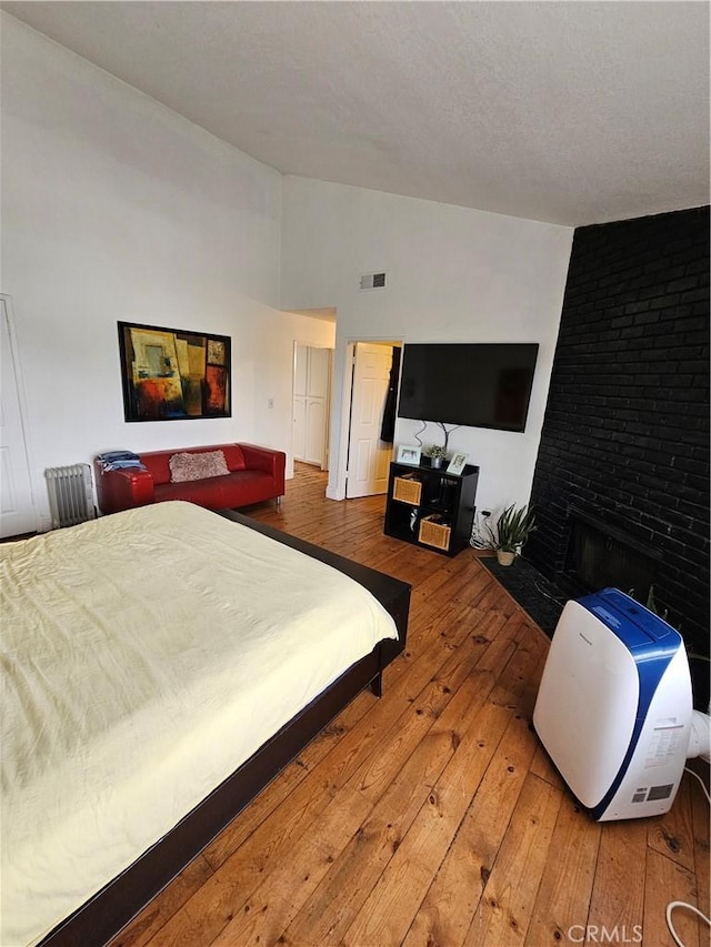 bedroom with hardwood / wood-style floors and a brick fireplace