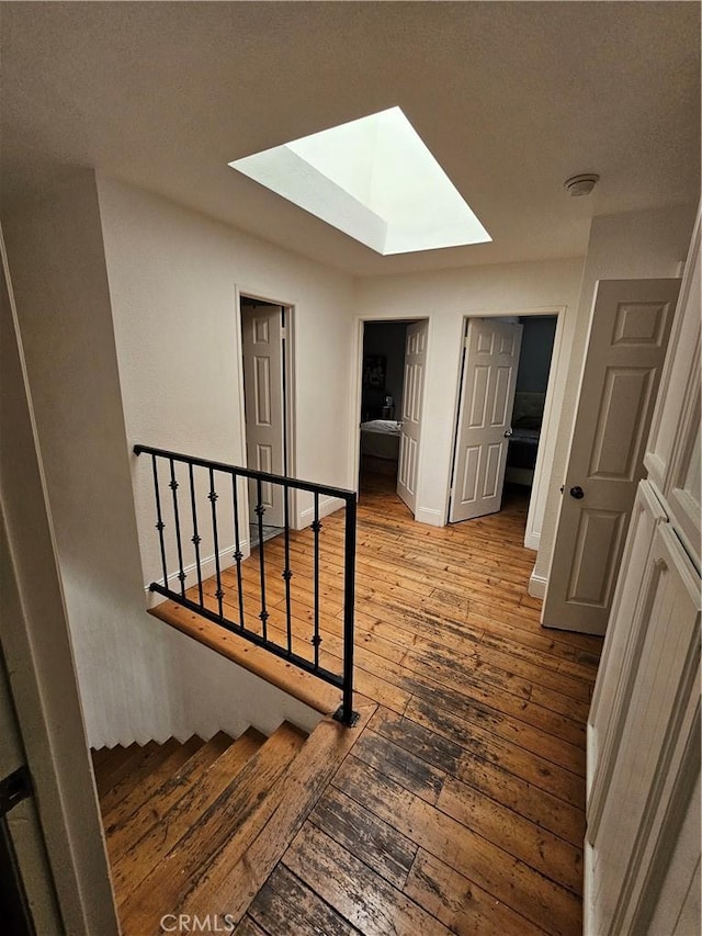 stairs with hardwood / wood-style flooring and a skylight