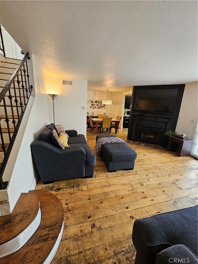 living room featuring hardwood / wood-style floors, a large fireplace, and a textured ceiling