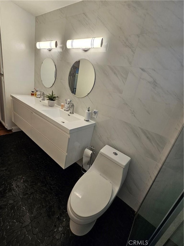 full bathroom with a sink, toilet, tile walls, and double vanity