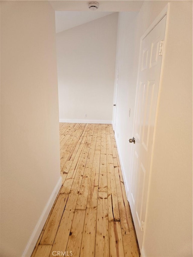 hall with light wood-style flooring and baseboards