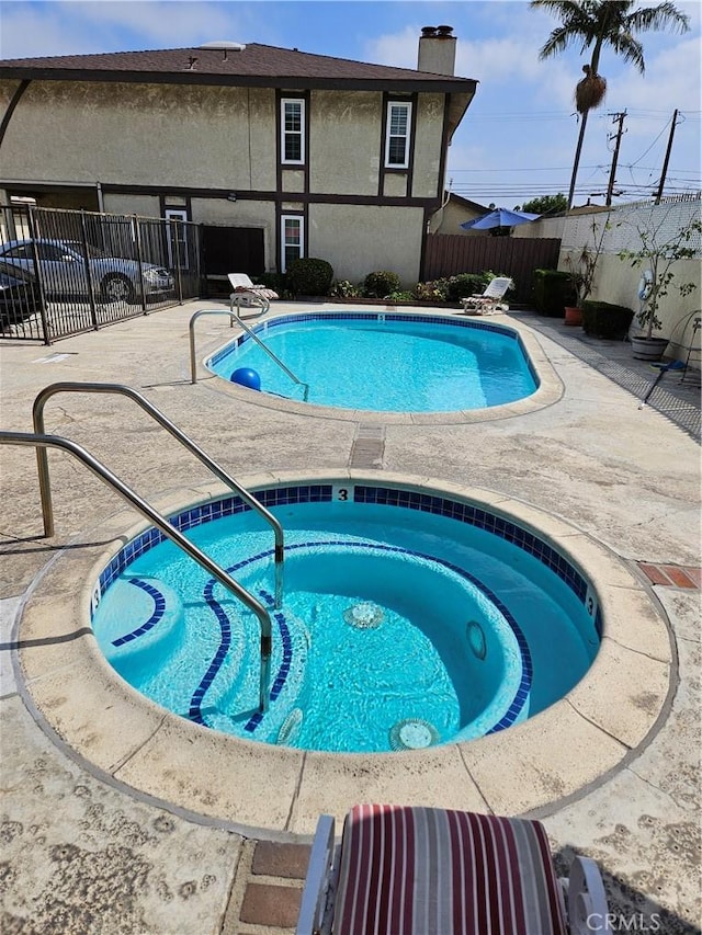 community pool with a patio, a community hot tub, and fence