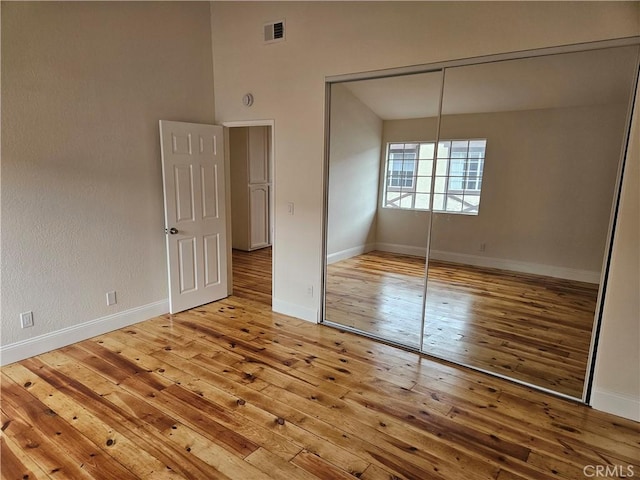 unfurnished bedroom with a closet, visible vents, baseboards, and wood-type flooring