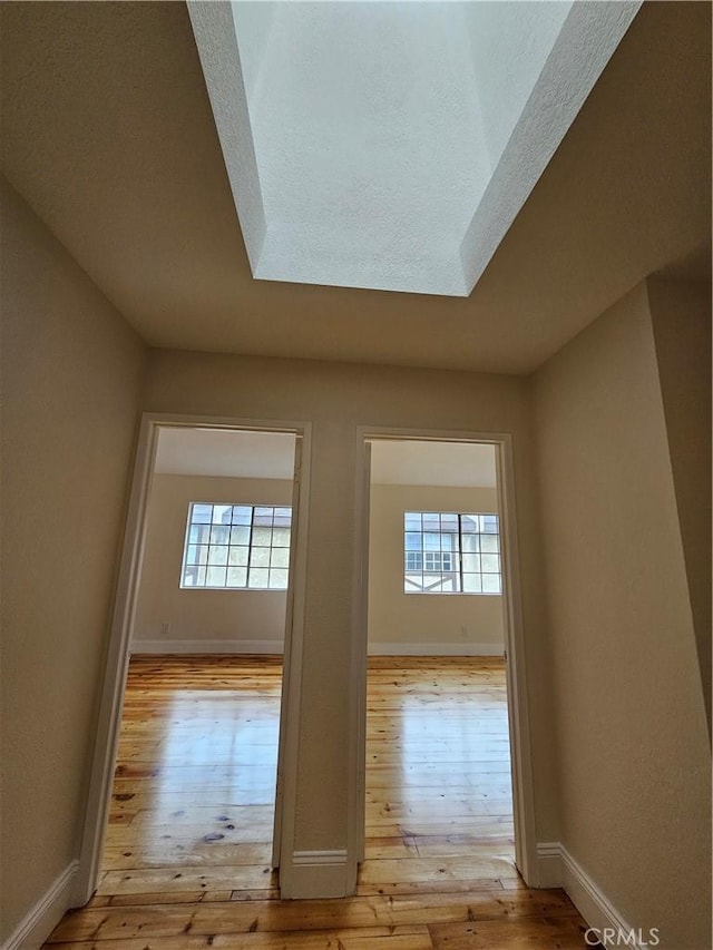 hall with baseboards and hardwood / wood-style floors